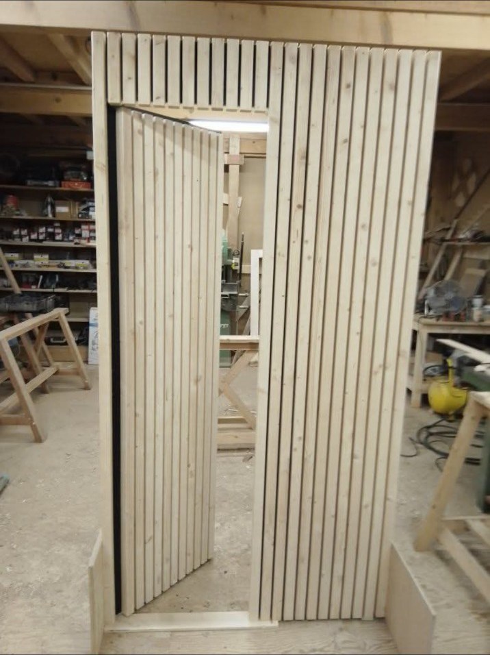 Claustra vertical en bois avec porte intégrée dans l’atelier